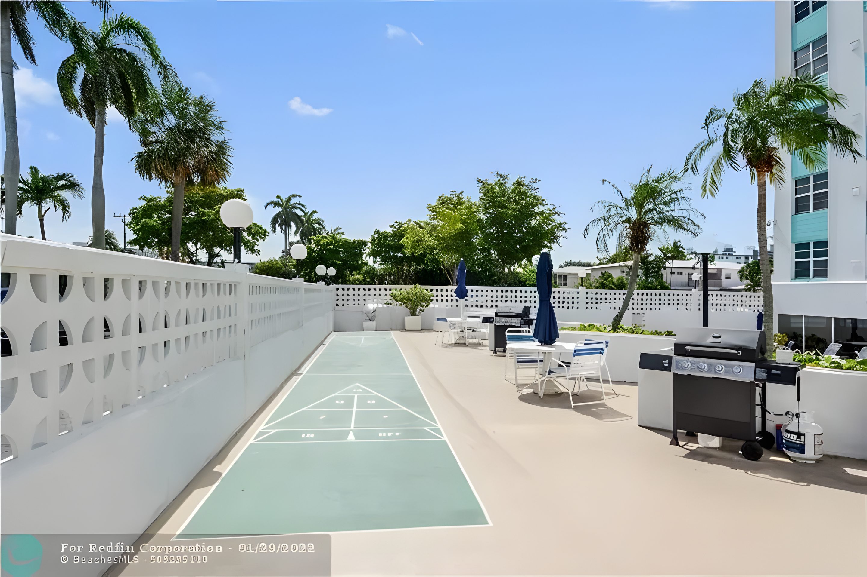 Shuffleboard courts beside a breeze-block screen wall and palms.